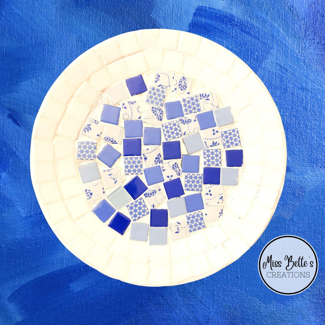 Blue and white handcrafted mosaic plate with intricate patterns, showcasing elegant design and fine craftsmanship.