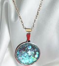 Teal blue crushed glass and silver round pendant necklace with a sleek, modern design.