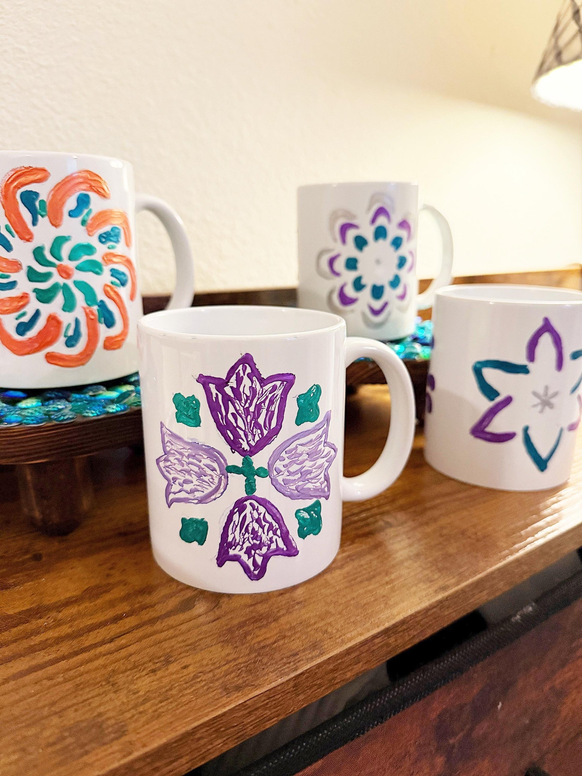 Handpainted coffee mugs with colorful floral designs, featuring unique artistic patterns on ceramic surfaces.