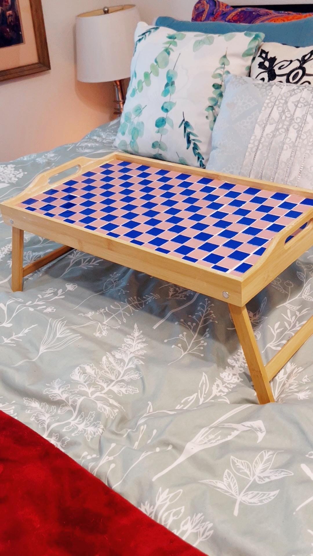 Handcrafted bamboo laptop tray with pink cushion for comfortable working or dining, designed for portability and style.