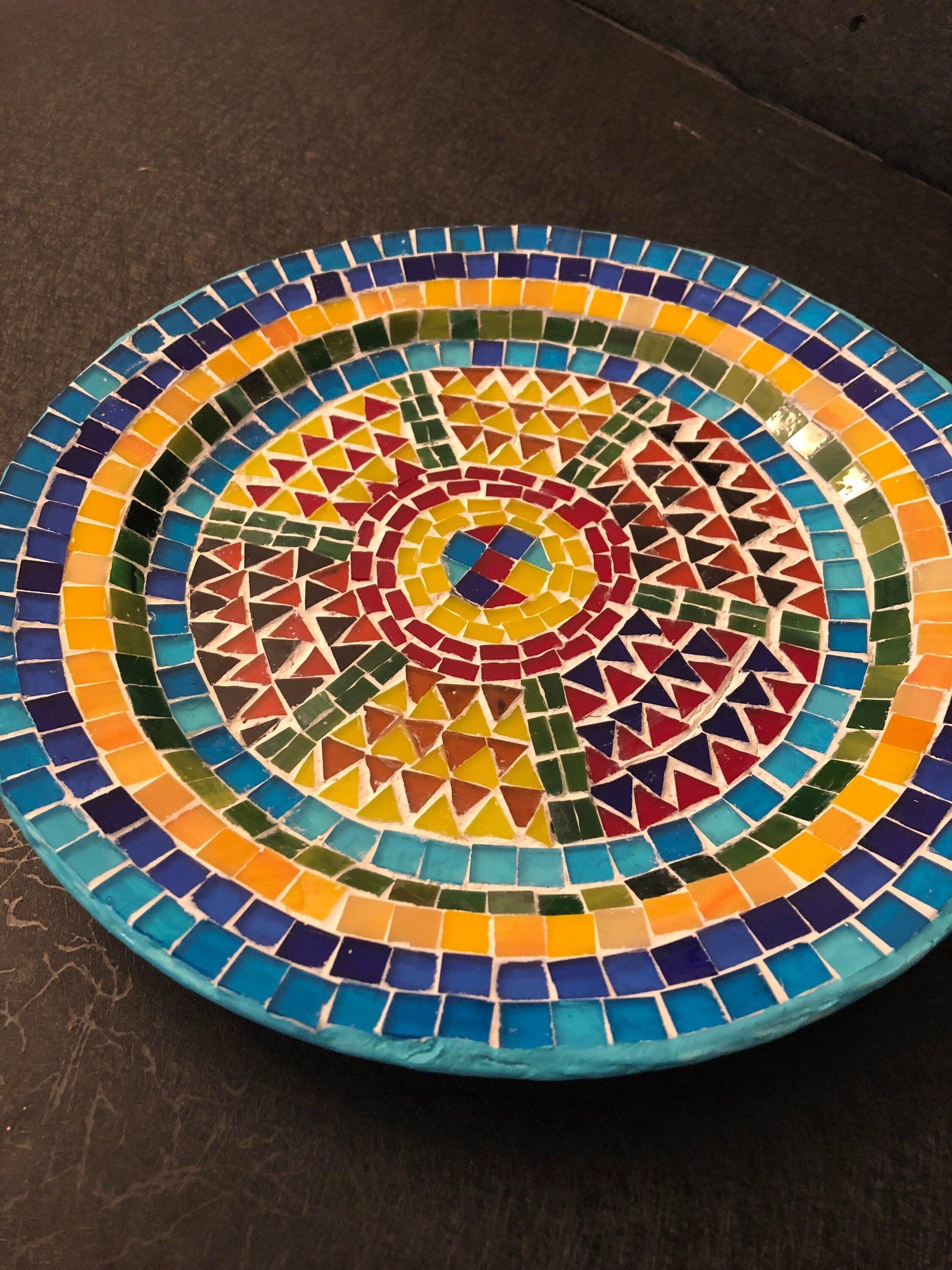 Handmade geometric mosaic plant plate with colorful tile design, perfect for indoor or outdoor planters.