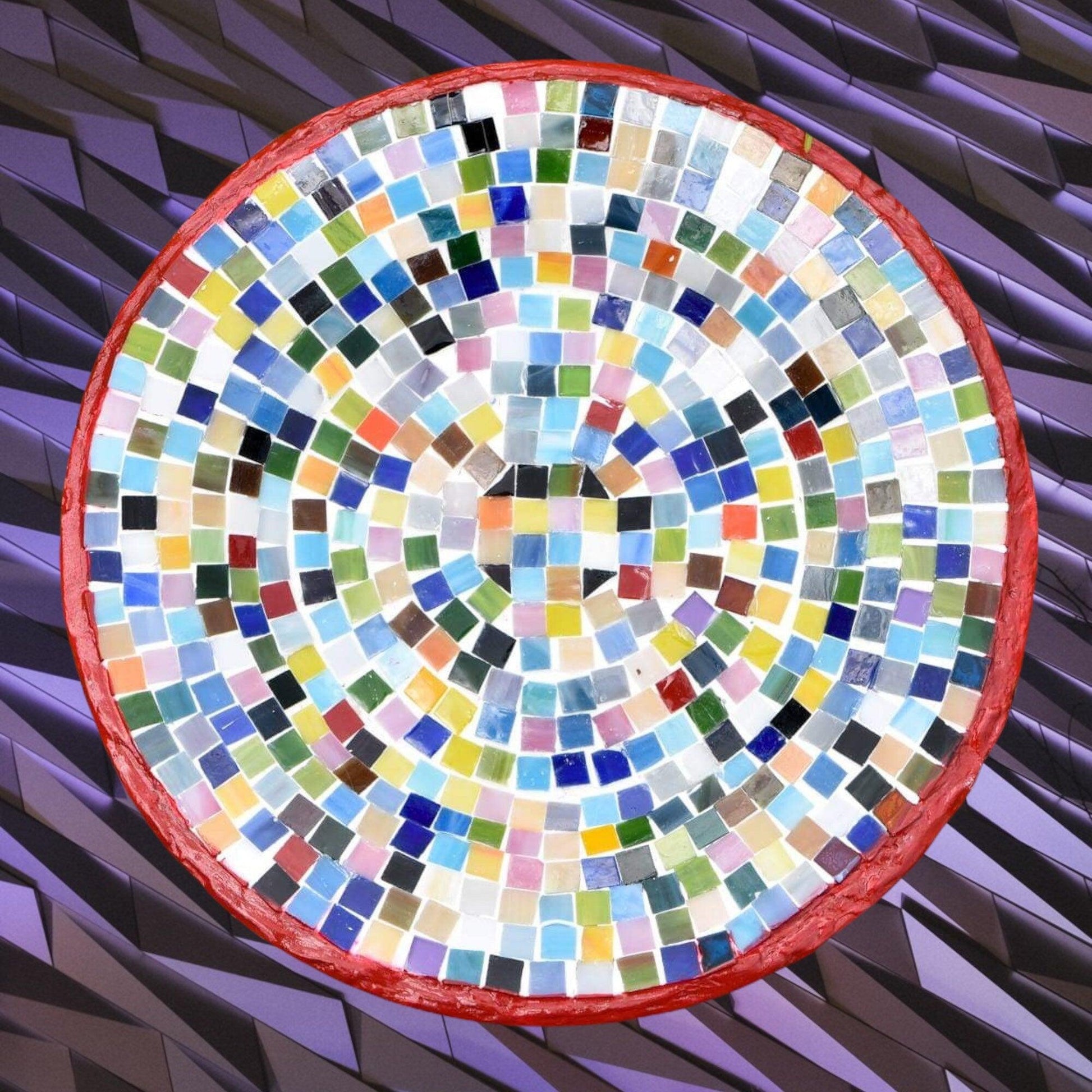 Vibrant handcrafted rainbow mosaic decorative plate with colorful glass pieces and intricate pattern.