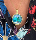 Ocean blue shell medallion necklace featuring a gold chain and ocean-inspired pendant, styled for casual or beachwear.