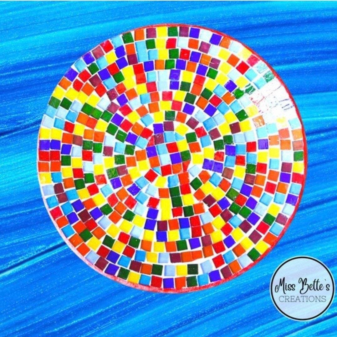 Colorful handcrafted rainbow mosaic stepping stone featuring vibrant glass tiles and intricate design for garden decoration.