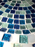 Iridescent turquoise mosaic glass wall art with geometric pattern, vibrant colors, and reflective surface for modern home decor.