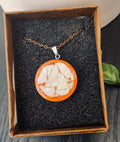 Artisan mosaic shell circle pendant with colorful shell inlay, hanging on a silver chain, showcasing intricate craftsmanship.