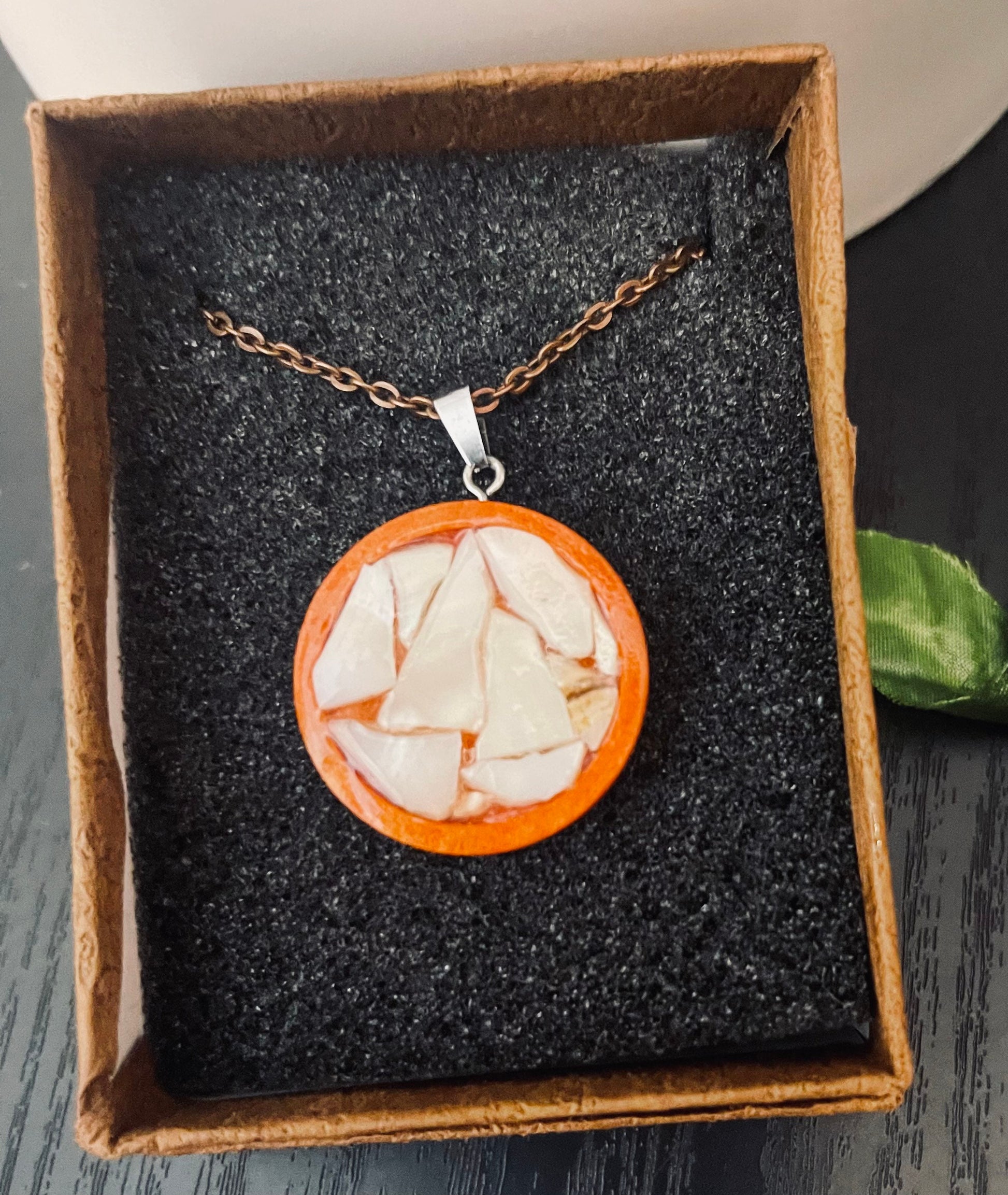 Artisan mosaic shell circle pendant with colorful shell inlay, hanging on a silver chain, showcasing intricate craftsmanship.