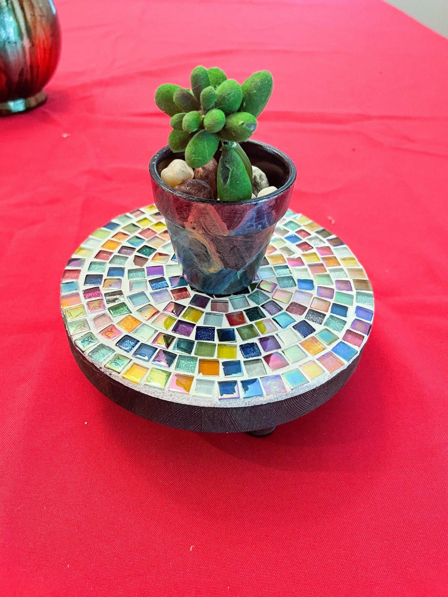 Small rainbow mosaic plant stand, handcrafted with colorful tiles, designed to hold potted plants beautifully.