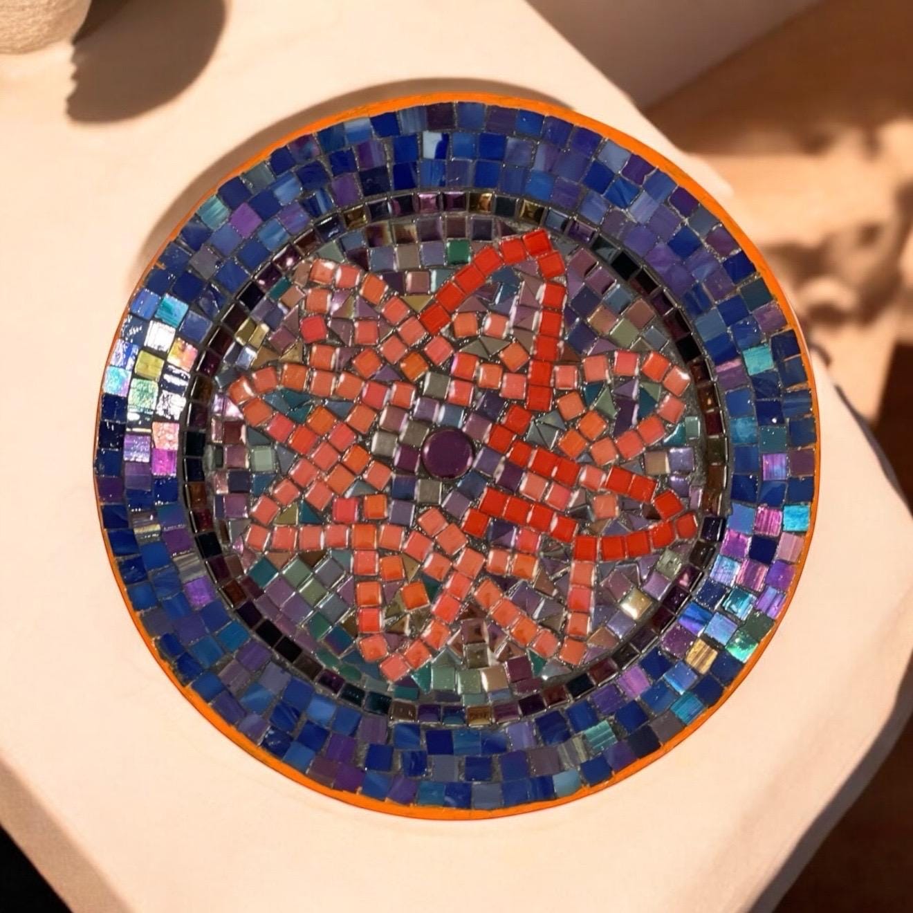 Handcrafted round mosaic wall art featuring colorful ceramic tiles, perfect for decorative indoor or outdoor wall display.