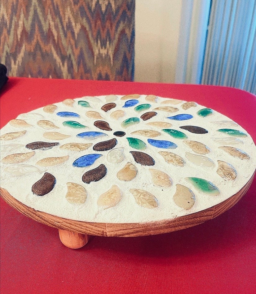 Handcrafted earth tone mosaic plant stand featuring colorful tiled design, ideal for displaying potted plants indoors or outdoors.