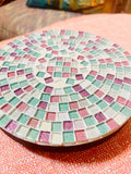 Handcrafted pink and green mosaic plant stand by Miss Bette's Creations with intricate tile patterns and sturdy metal legs.