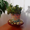 Handcrafted petal mosaic wooden plant stand with colorful petal designs, perfect for displaying indoor plants.
