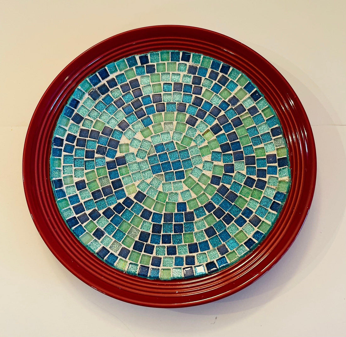 Deep crimson ceramic plate with ocean breeze mosaic pattern, showcasing vibrant blue and turquoise tile designs.