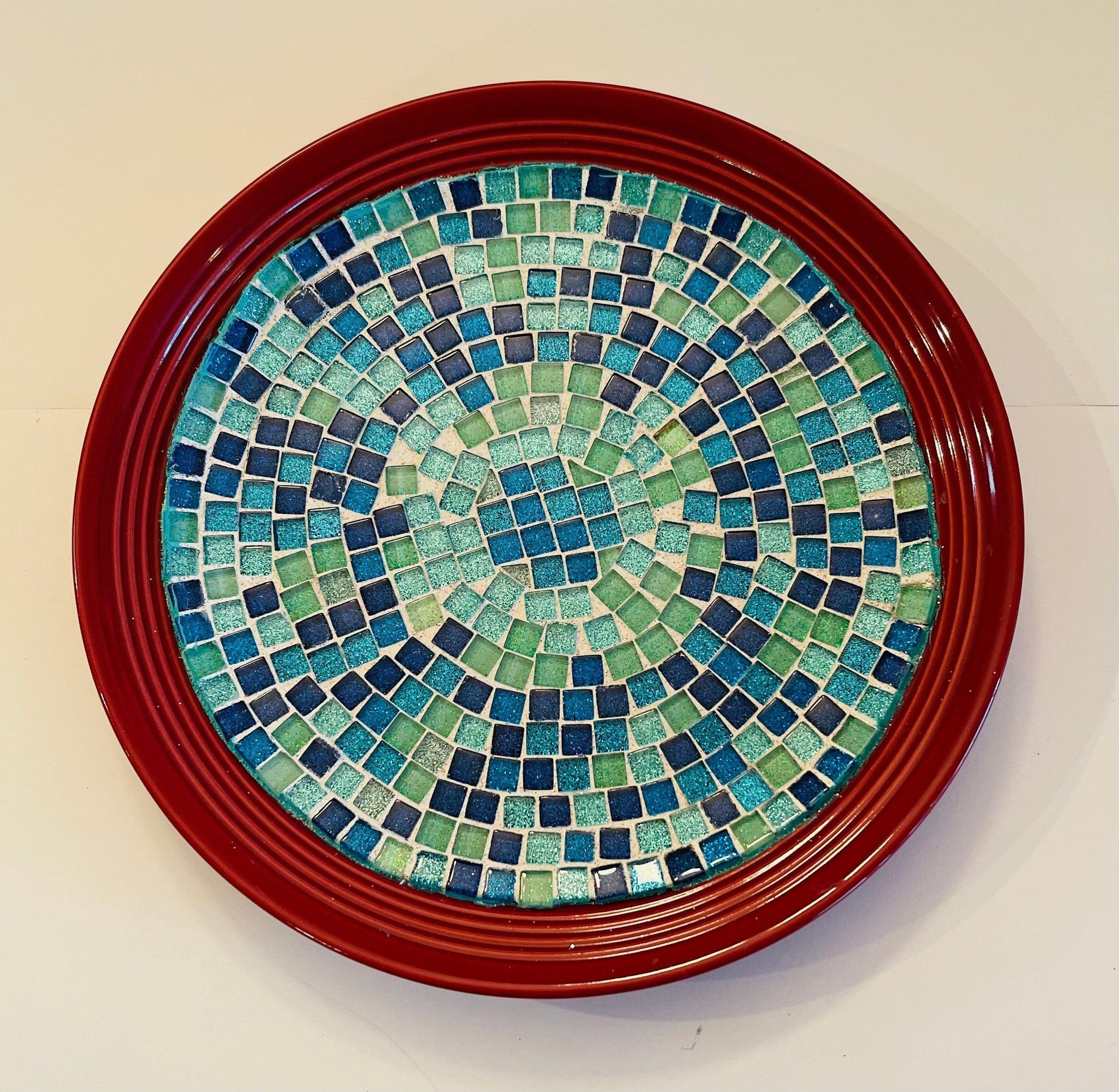 Ocean Breeze mosaic design on a deep crimson ceramic plate, featuring vibrant, intricate patterns and a glossy finish.