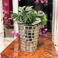 Artificial snake plant in a silver mosaic planter, showcasing green spiky foliage and decorative silver tile pattern.