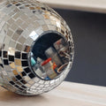 Hanging disco ball planter with artificial pink carnations, decorative floral display in a shiny, reflective sphere.