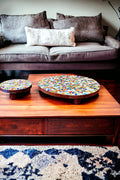 Colorful handcrafted round rainbow mosaic plant stand with metal legs, designed to hold potted plants and decorative greenery.