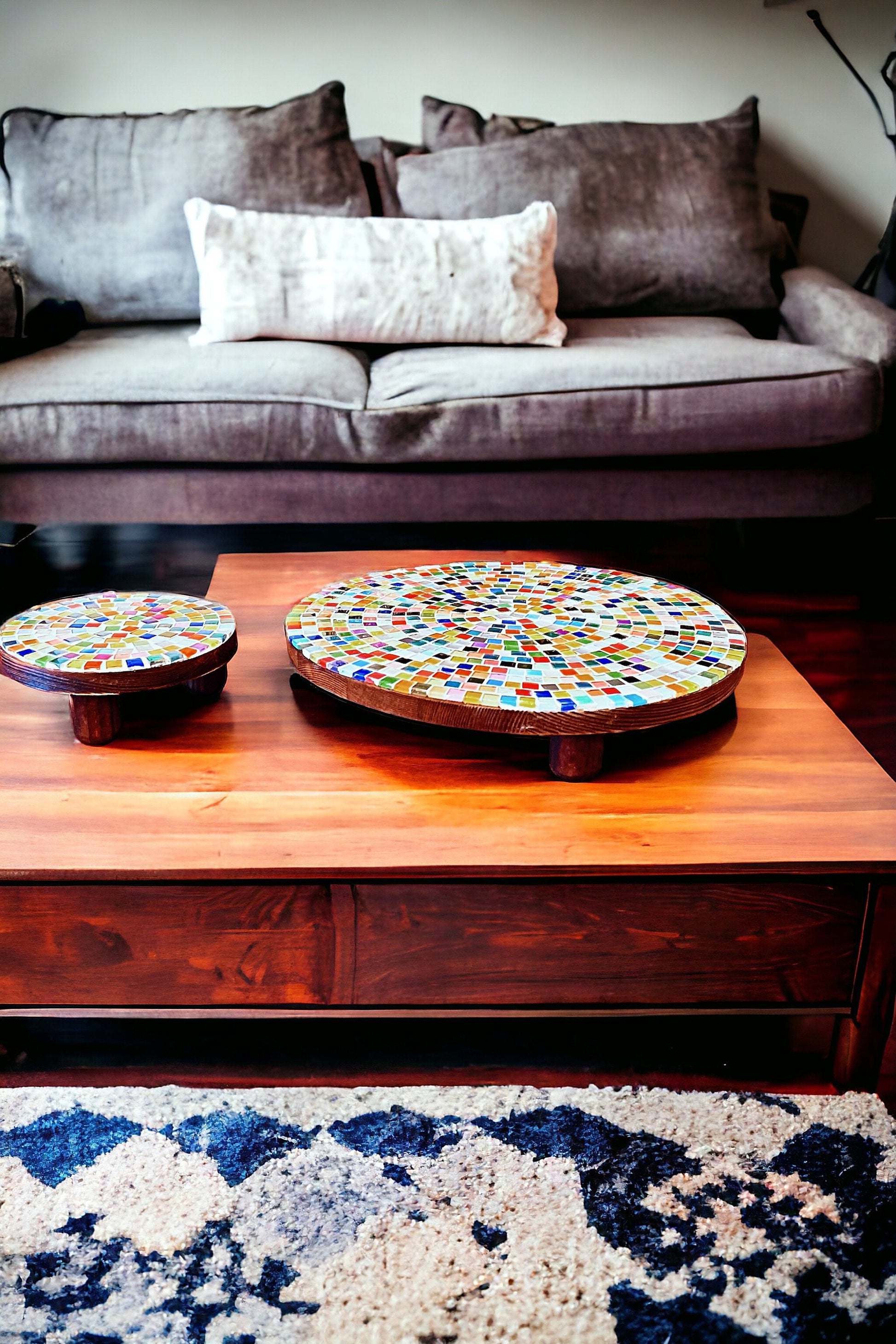 Colorful handcrafted round rainbow mosaic plant stand with metal legs, designed to hold potted plants and decorative greenery.