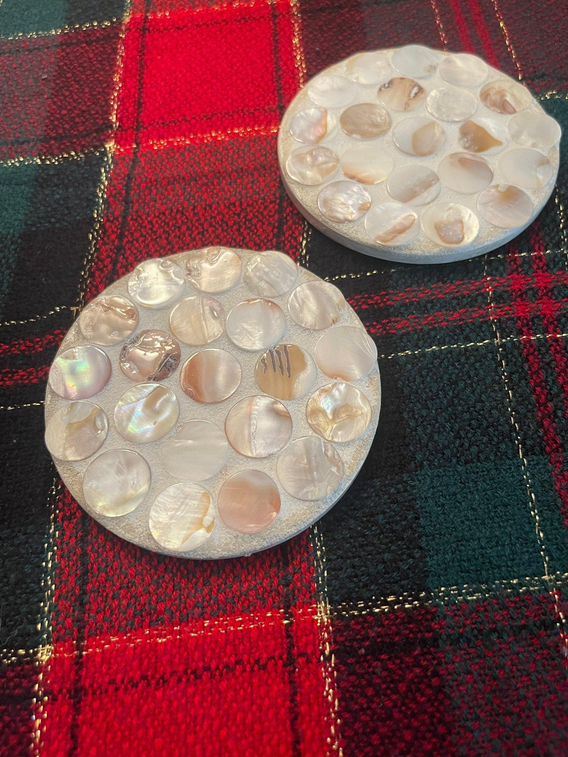 Set of four mother of pearl mosaic coasters with intricate iridescent patterns, ideal for protecting surfaces in elegant settings.