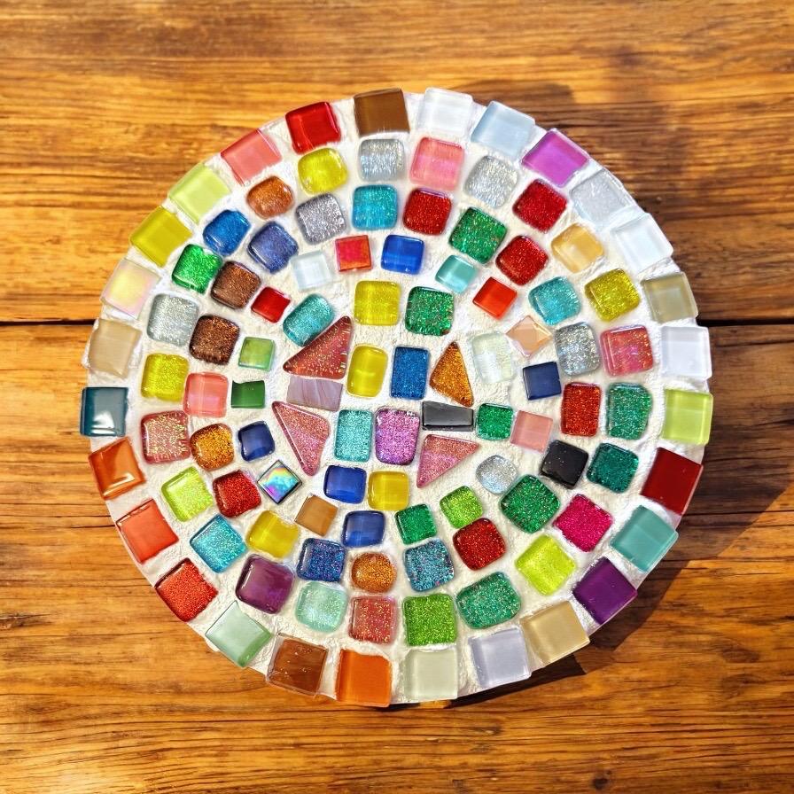 Handcrafted blue and amber mosaic plant stand with intricate tile design for supporting indoor or outdoor plants.