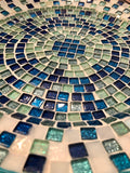 Iridescent turquoise mosaic glass wall art with vibrant, reflective tiles arranged in an artistic pattern for home decor.