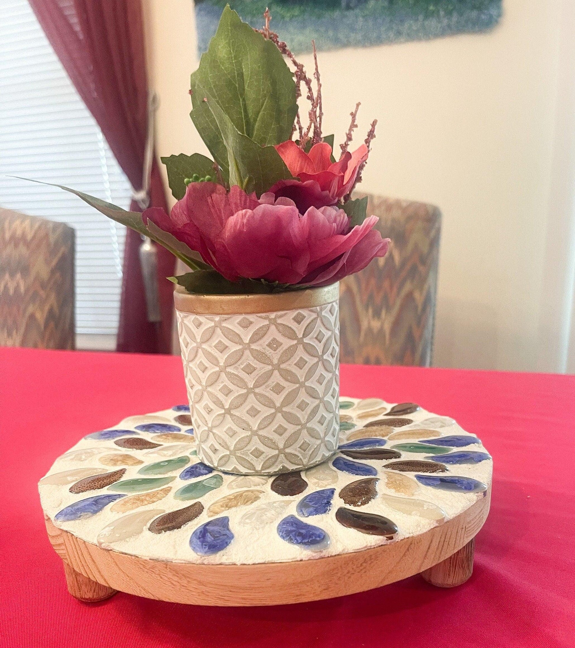 Handmade earth tone mosaic plant stand with three legs, suitable for displaying potted plants indoors or outdoors.