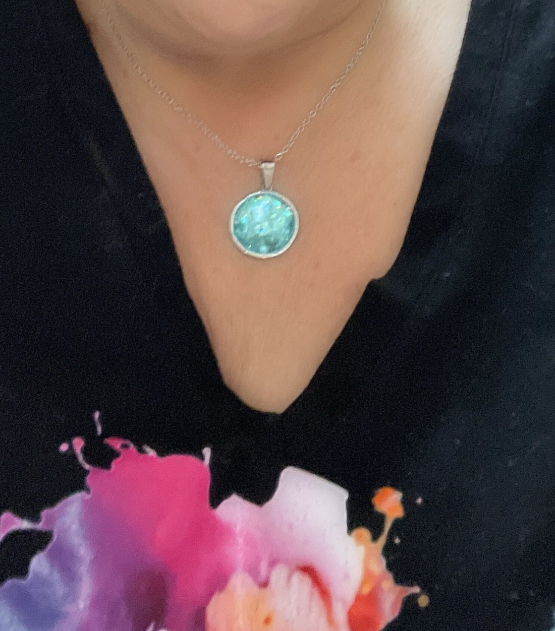 Teal blue crushed glass and silver round pendant necklace with a sleek chain, stylish jewelry piece for women.