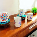 Handpainted coffee mugs with colorful floral designs, featuring artistic patterns on ceramic surfaces.
