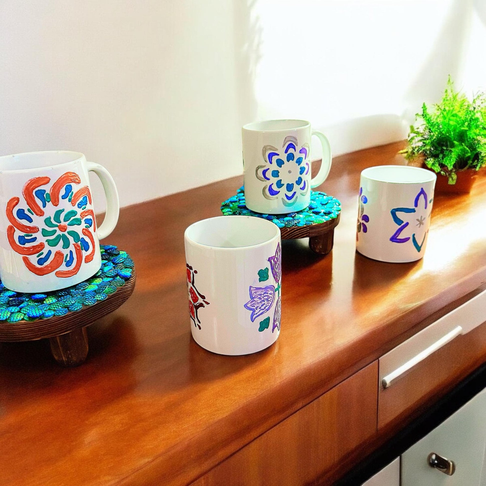 Handpainted coffee mugs with colorful floral designs, featuring artistic patterns on ceramic surfaces.