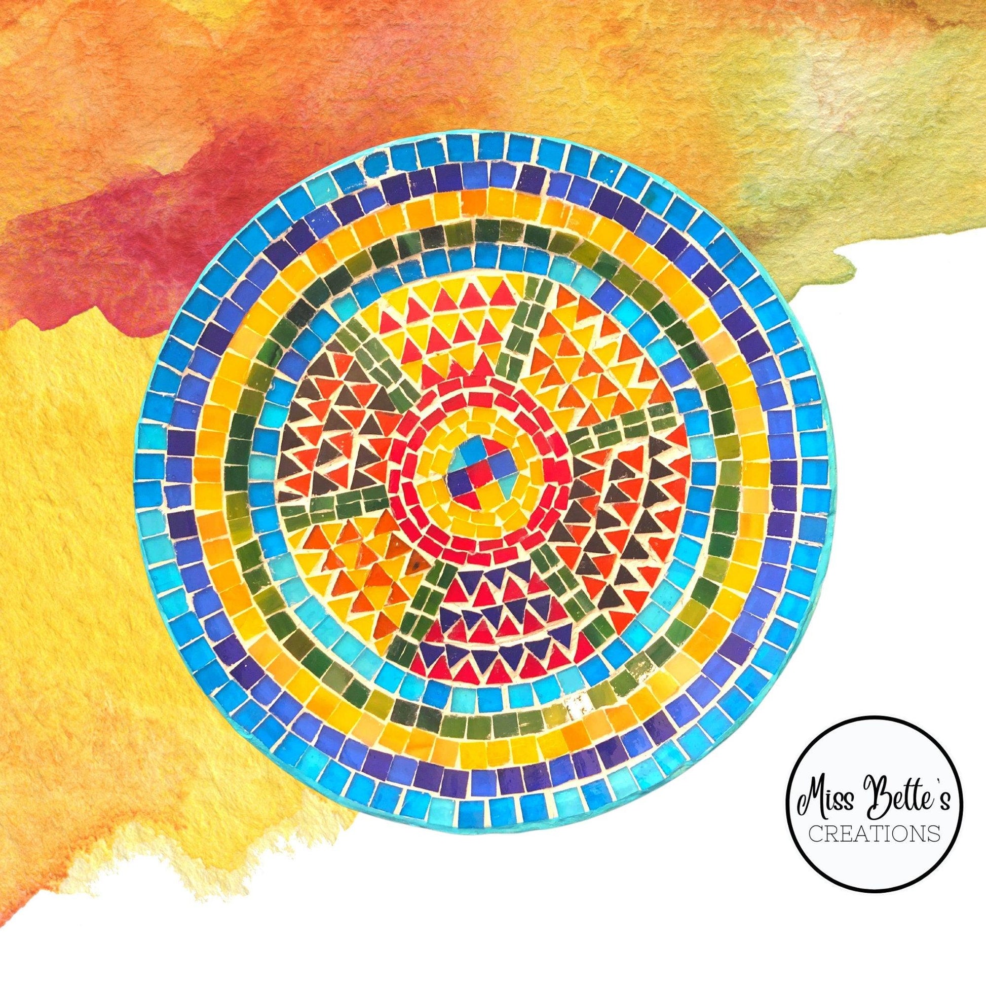 Handmade geometric mosaic plant plate with colorful tile design, used for displaying and holding potted plants.