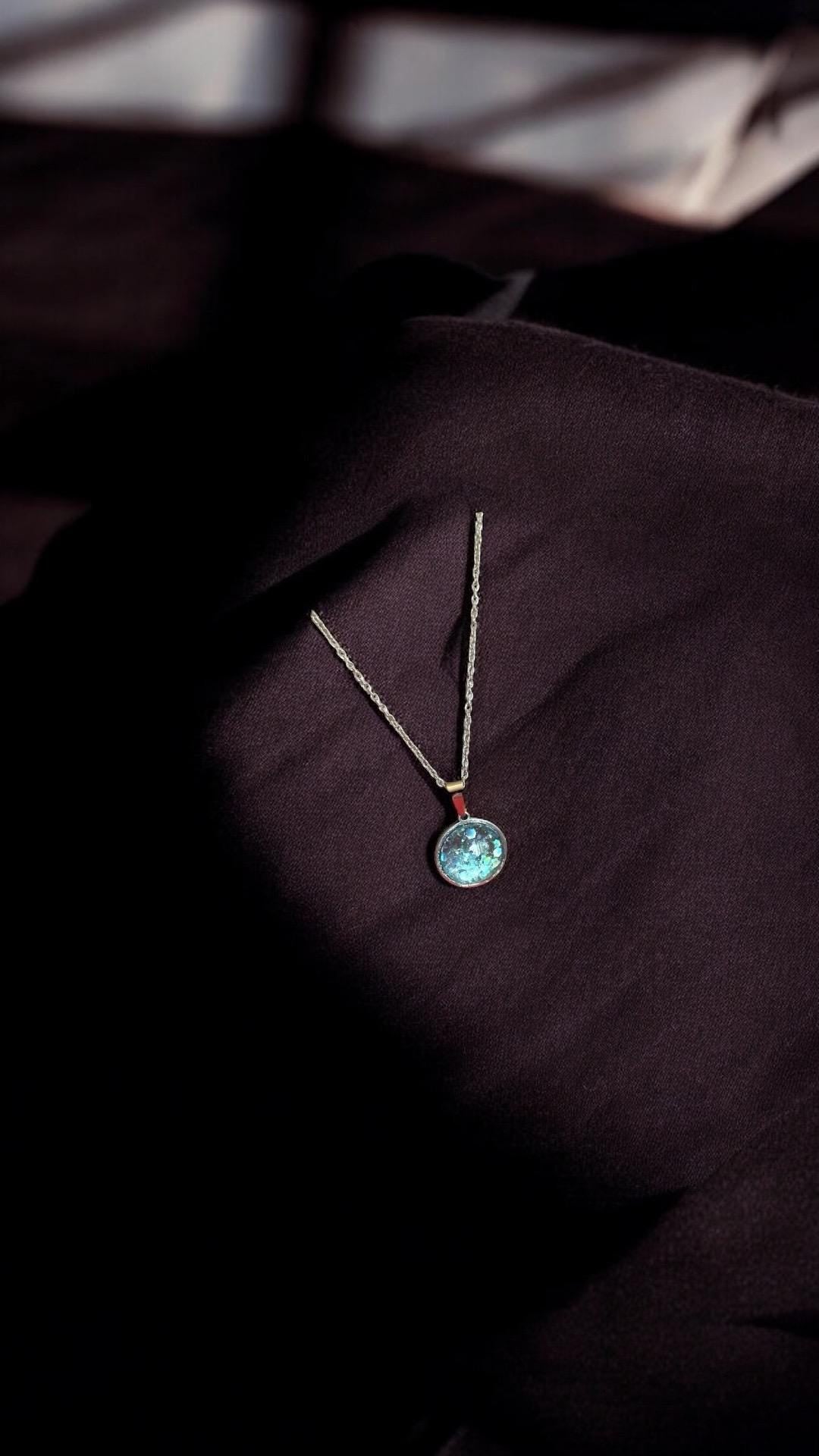 Sparkling aqua blue pendant necklace featuring a shimmering gemstone on a silver chain, elegant jewelry accessory.