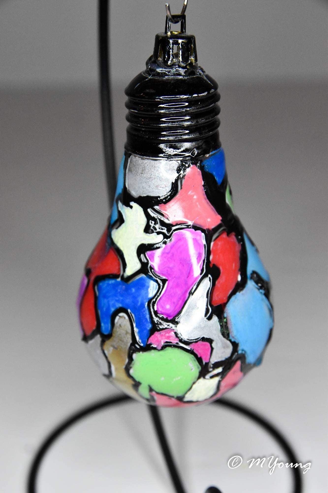 Handmade stained glass mosaic light bulb ornament with colorful holiday design, ideal for festive decorations.