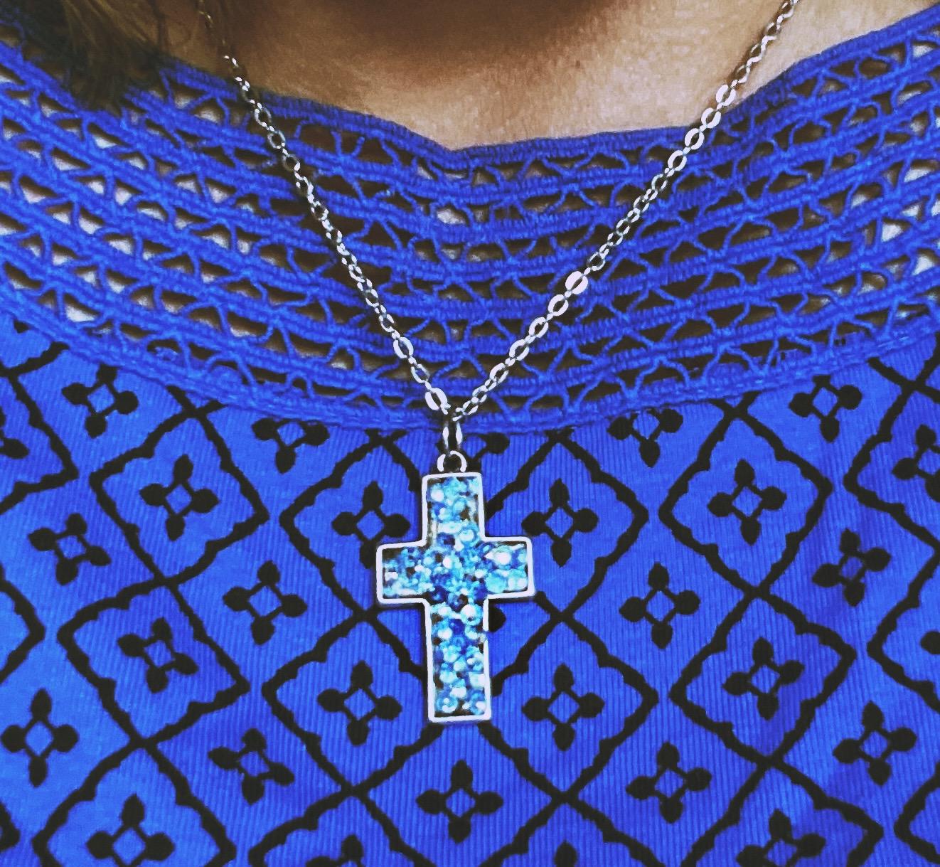 Sparkling blue crystal cross necklace with silver chain, elegant jewelry piece featuring dazzling blue gemstones and intricate design.