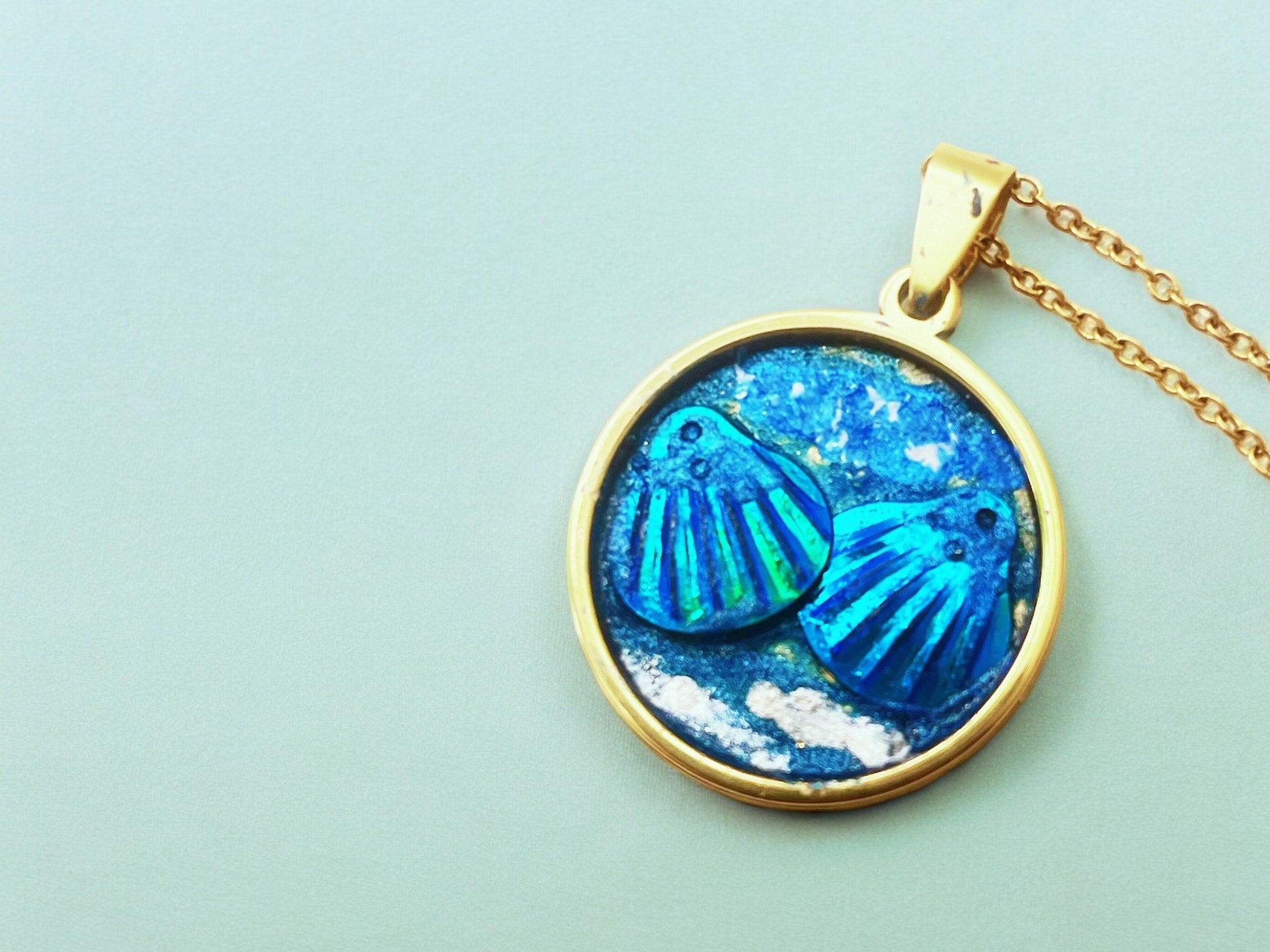 Ocean blue shell medallion necklace with intricate design, featuring a large shell pendant on a delicate chain.