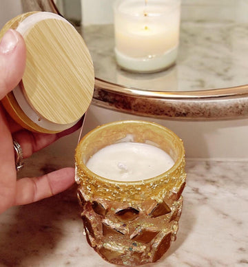 Handcrafted eucalyptus scented candle in a gold mosaic glass jar, held in hand, showcasing artisanal design and elegant craftsmanship.