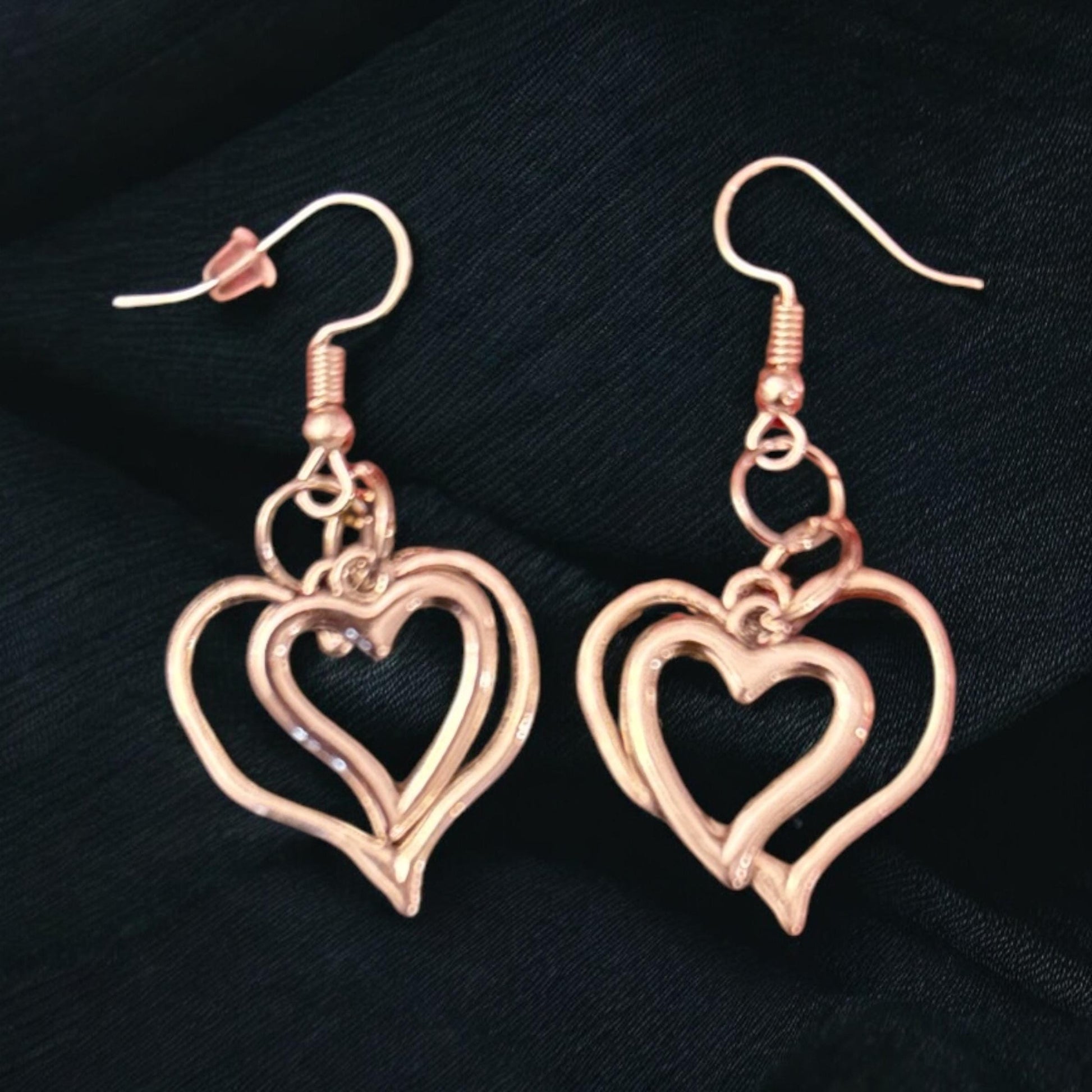 Triple layer heart dangle earrings with gold finish, featuring layered heart charms and delicate hooks for a stylish look.