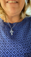 Sparkling blue crystal cross necklace with silver chain, elegant jewelry accessory featuring a vibrant blue crystal cross pendant.
