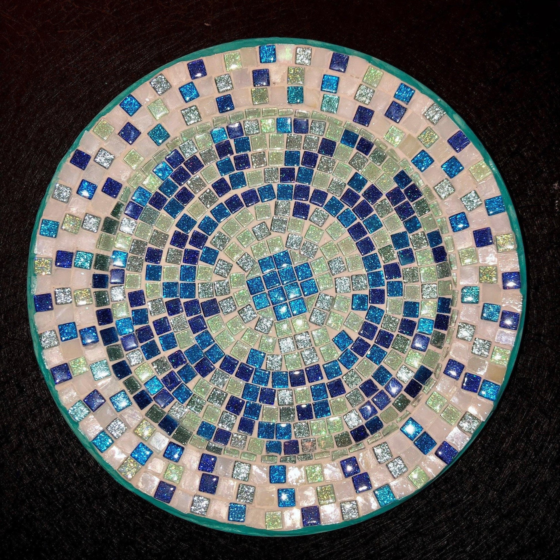 Iridescent turquoise mosaic glass wall art with vibrant, shimmering tiles arranged in an intricate pattern.