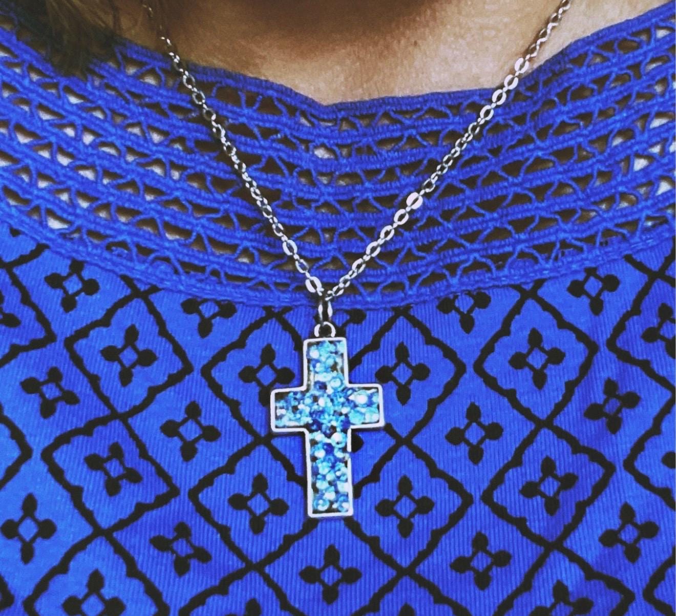 Sparkling blue crystal cross necklace featuring a silver chain and detailed pendant, elegant jewelry accessory.