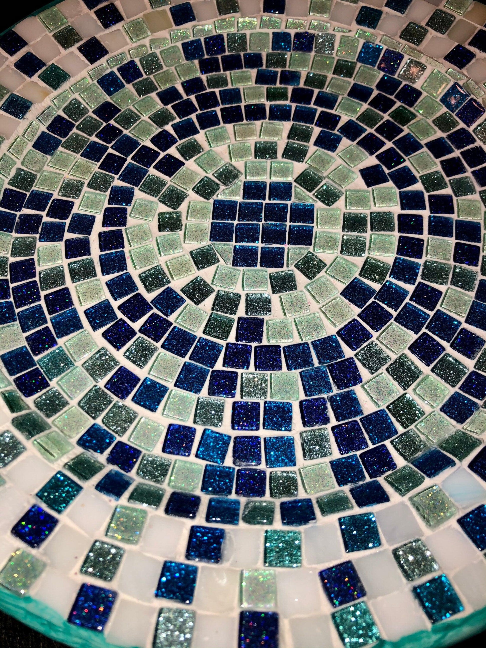Iridescent turquoise mosaic glass wall art featuring colorful glass tiles arranged in an eye-catching geometric design.