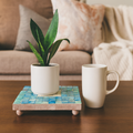 Handcrafted square turquoise plant stand with wooden legs, designed to hold potted indoor plants.