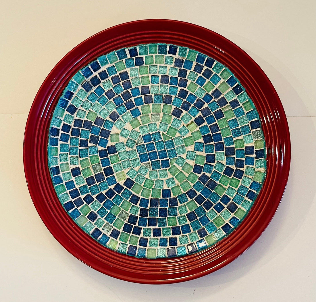 Deep crimson ceramic plate with ocean breeze mosaic pattern, showcasing vibrant blue and turquoise tile designs.