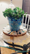 Handcrafted botanical petal mosaic plant stand featuring colorful floral tile design for indoor or outdoor use.