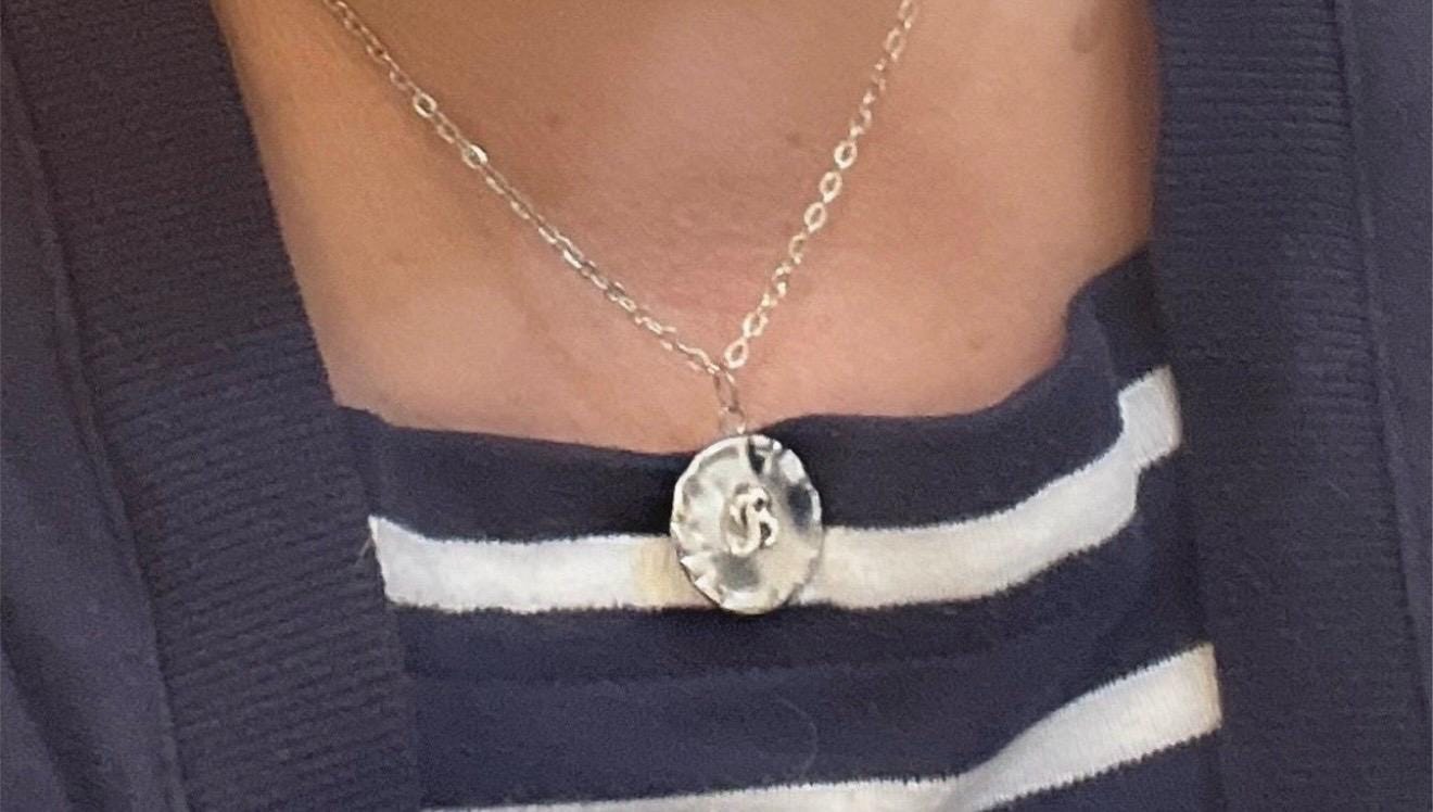 Vintage initial charm necklace with a silver chain and personalized initial pendant, styled for a classic, elegant look.
