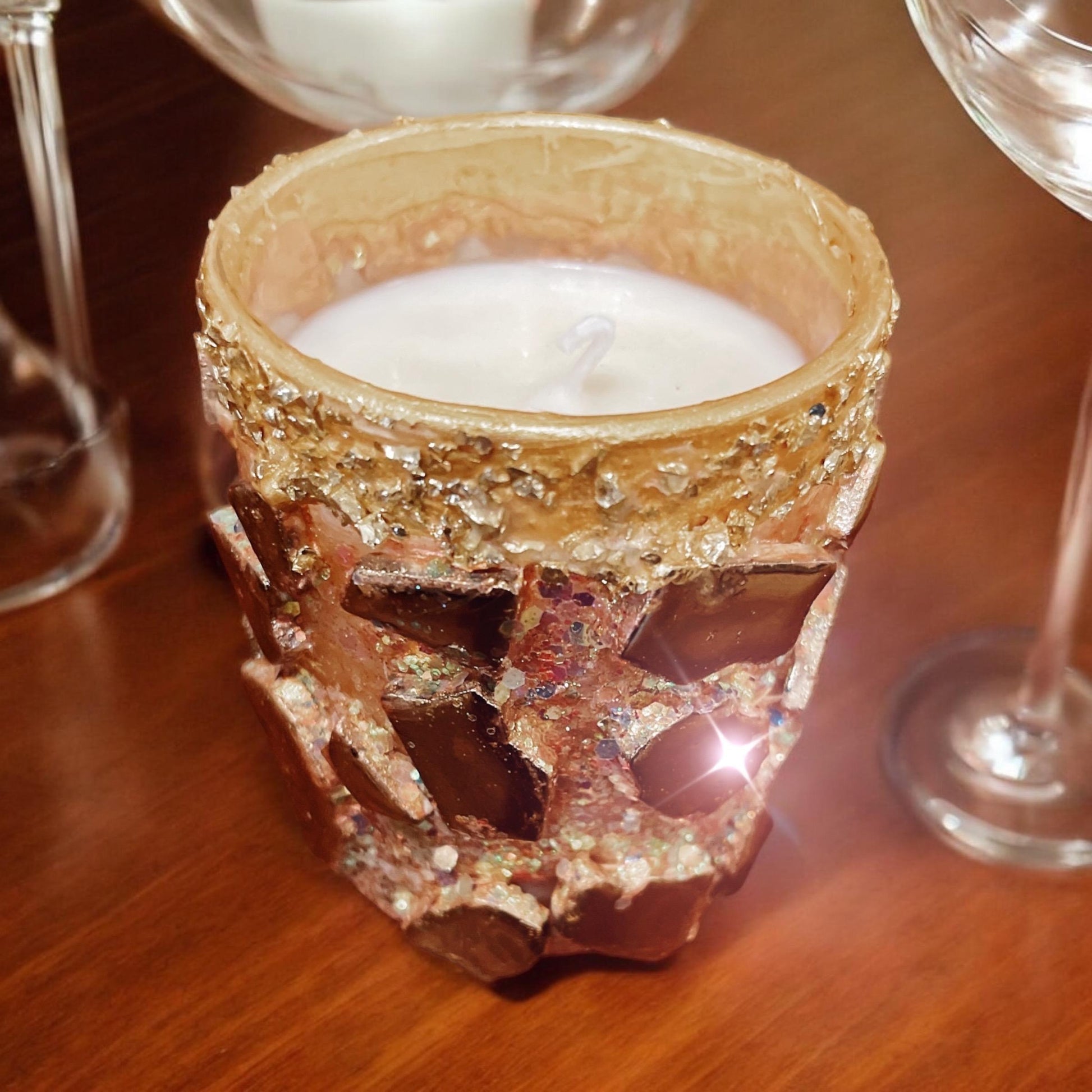Handcrafted eucalyptus scented candle in a gold mosaic glass jar, held in a person's hand for a warm, natural ambiance.