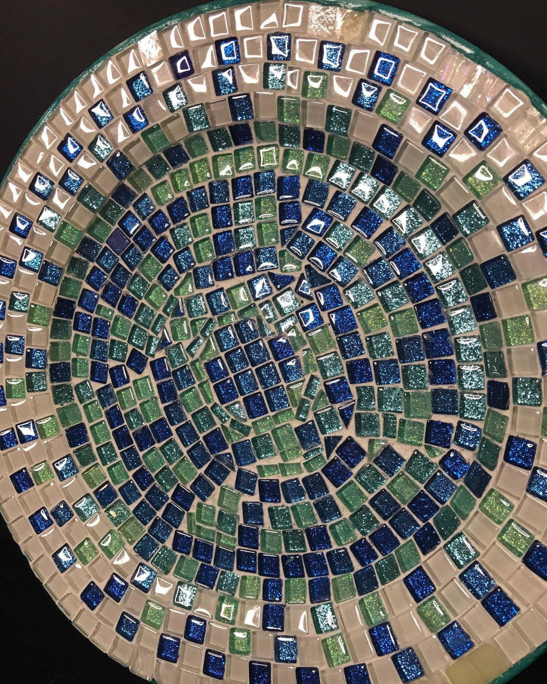 Iridescent turquoise mosaic glass wall art with vibrant, shimmering tiles arranged in an intricate pattern.