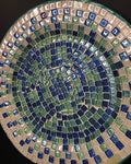 Iridescent turquoise mosaic glass wall art with colorful, reflective tiles arranged in a decorative pattern.