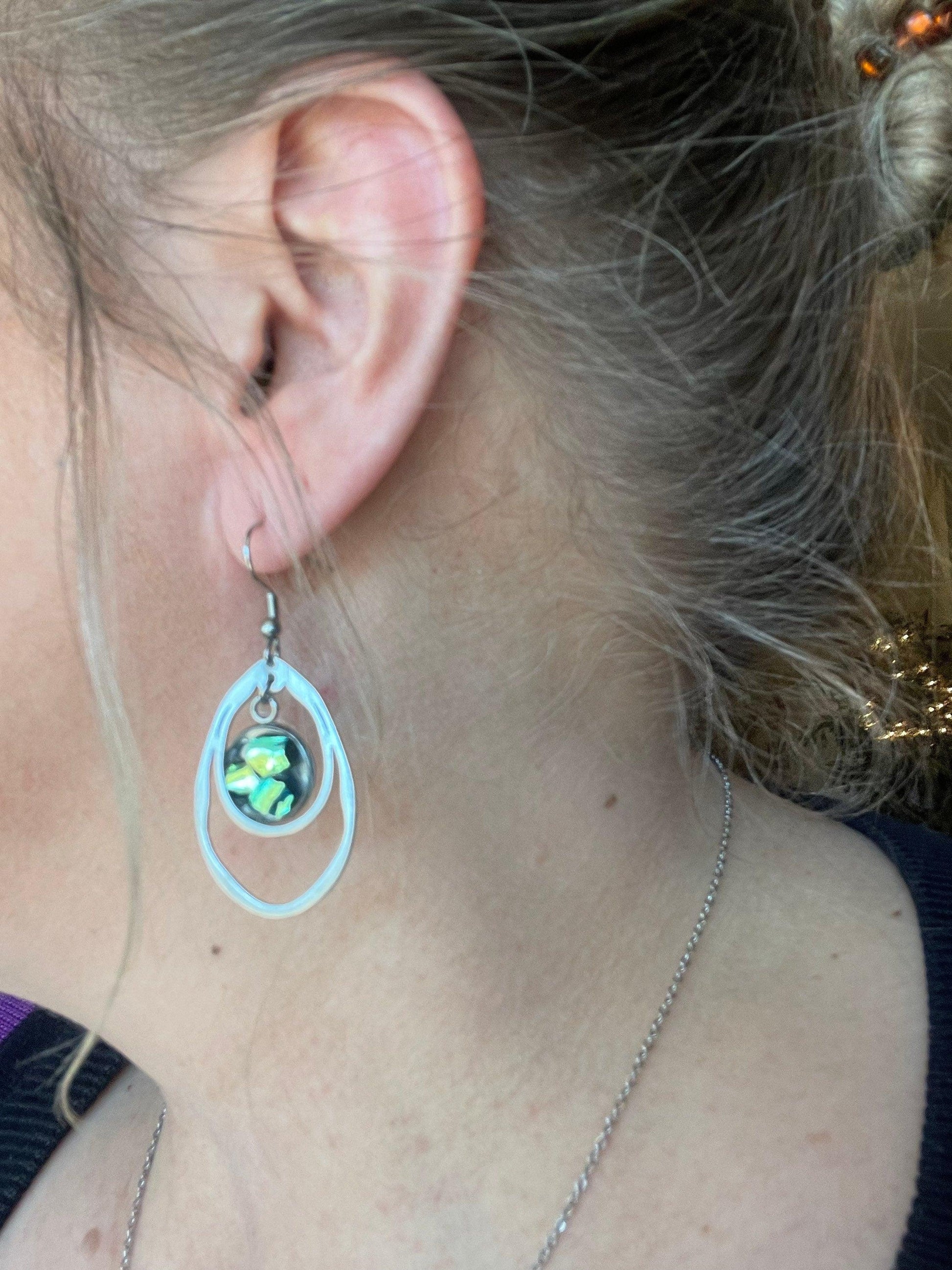 Double teardrop earrings featuring iridescent abalone shells, crafted in a stylish design with silver-tone accents.