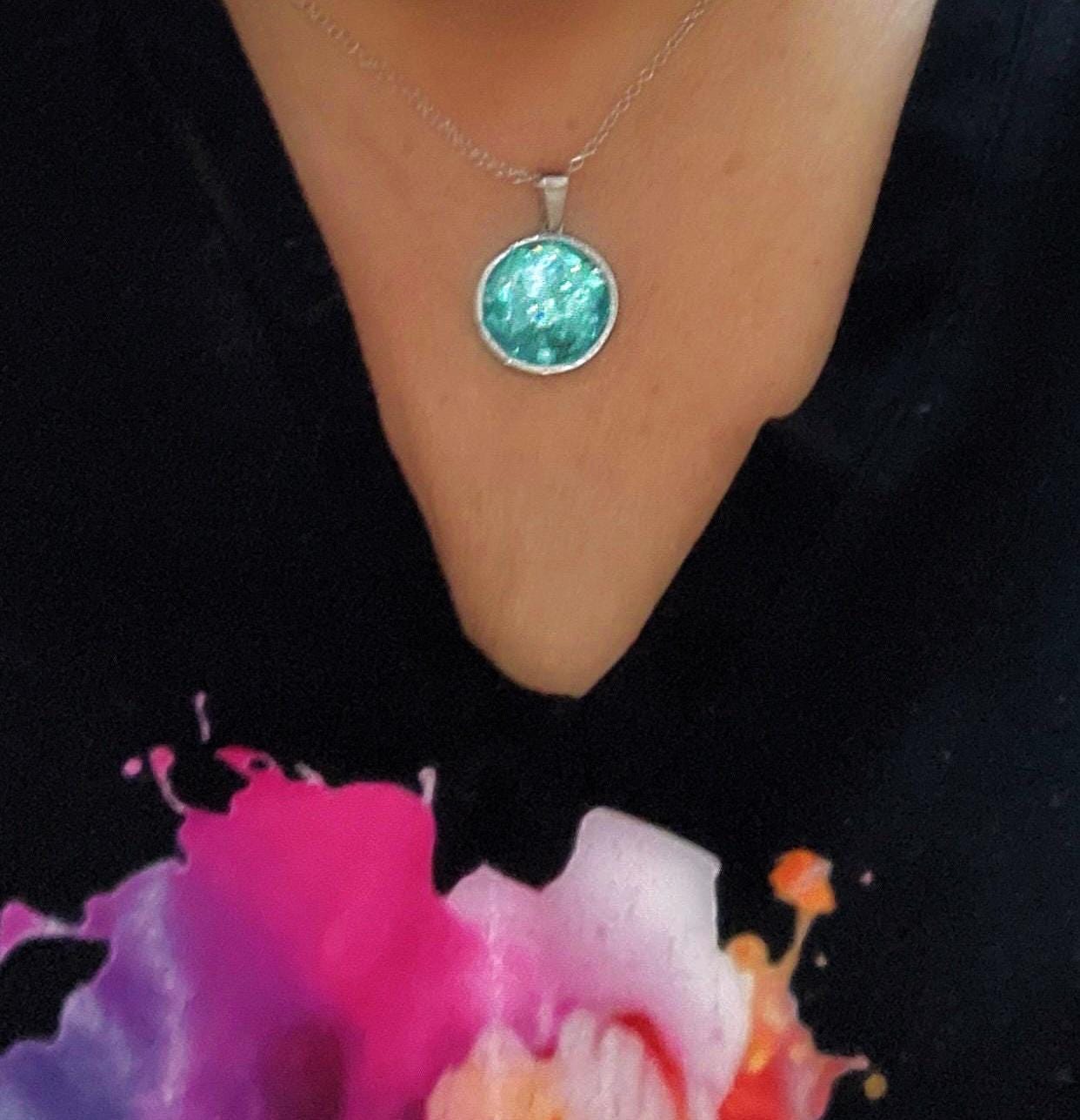 Sparkling aqua blue pendant necklace with silver chain, featuring a shimmering gemstone, stylish jewelry accessory.