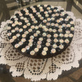Handmade black and white iridescent mosaic plant stand with intricate tile pattern, designed to hold potted plants beautifully.